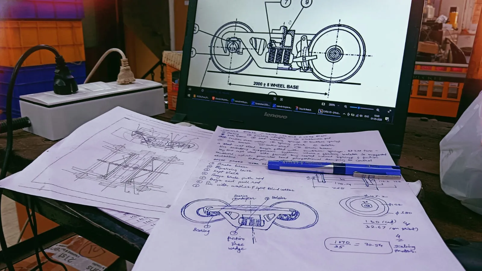 Hand sketches and scaling calculations for a CASNUB bogie beside a reference drawing on a laptop